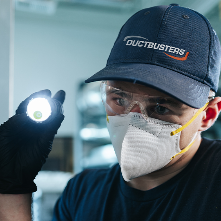 DUCTBUSTERS technician in an air duct cleaning